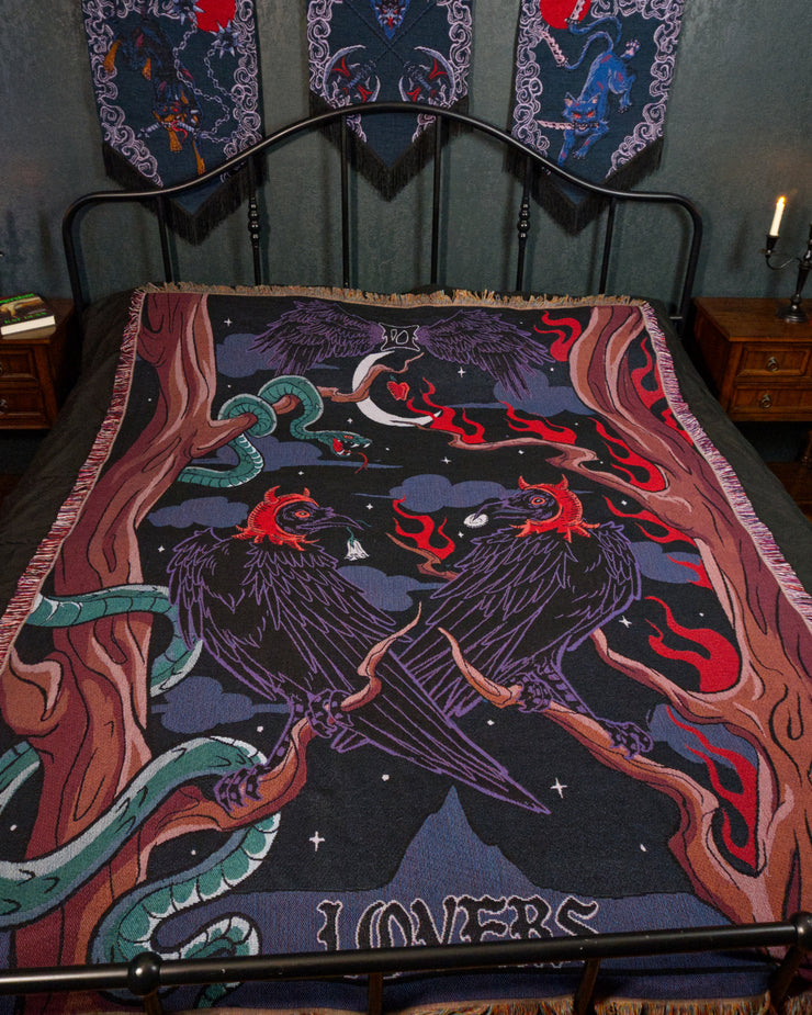 Temptation laying on a black metal bed in a gothic bedroom. Three banners hang above with a candelabra on each side