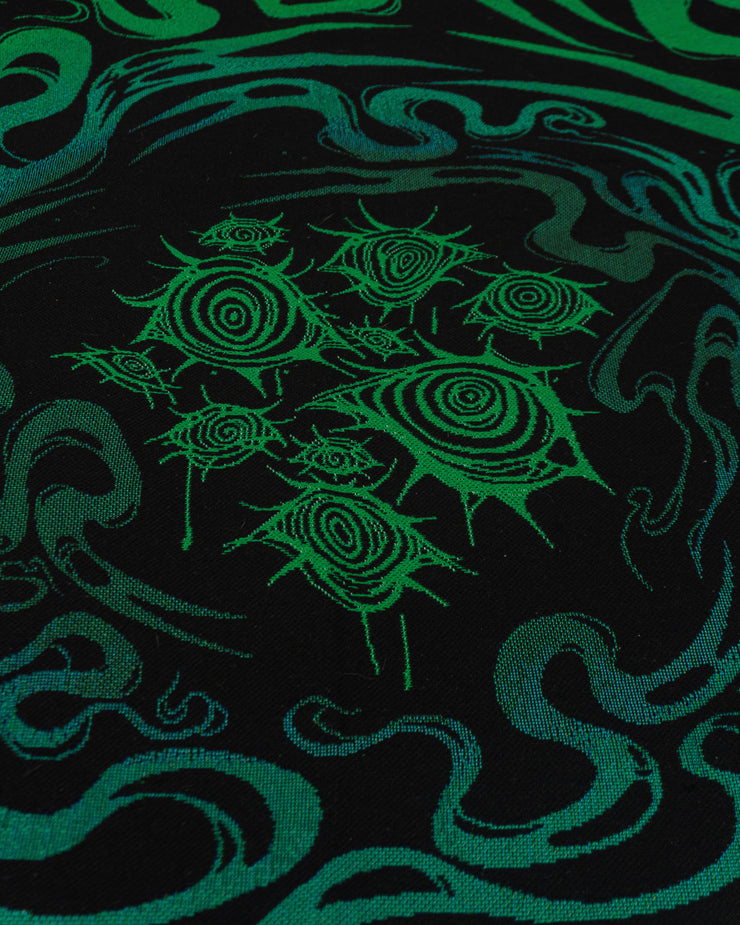 Underworld woven detail close up, featuring ten vibrant green eyes with spiraling irises. Ghosts swirl around the outside of the eye cluster.